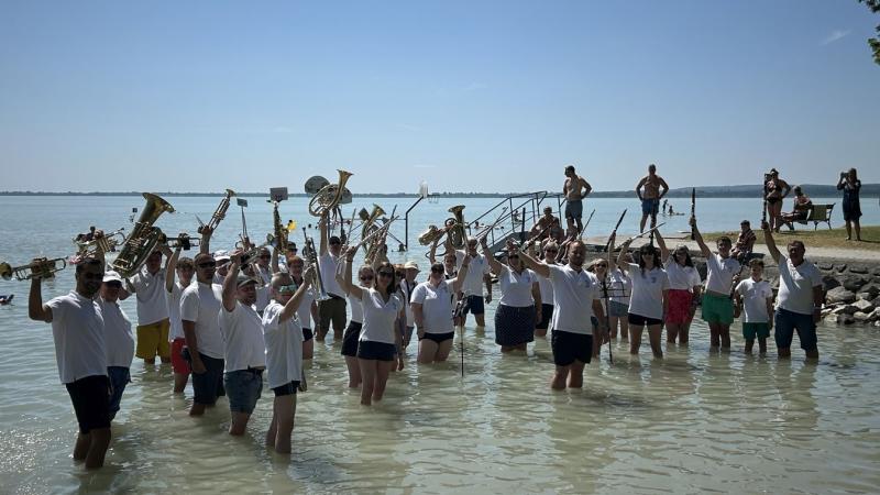 A Balaton vízébe lépve a tapsok zaja kísért.